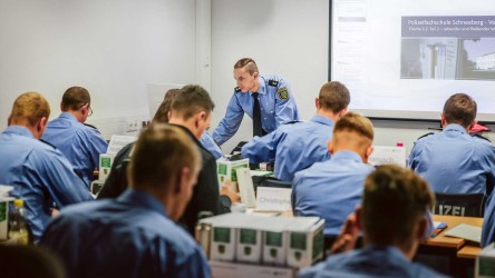 Mehrere Polizeiazubis und ein Ausbilder beim Unterricht in einem Schulungsraum der Polizeifachschule Schneeberg.