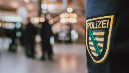 Im Fokus das Polizei Sachsen-Wappen am Ärmel einer Uniform.