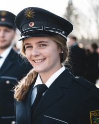 Ausbildungs-Absolventin Johanna lächelt kurz vor ihrer Ernennung zur Polizeimeisterin in die Kamera.