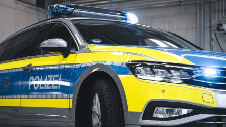 Ein Detailbild vom Streifenwagen. Das Blaulicht ist aktiviert, der „Polizei“-Schriftzug ist zu lesen.
