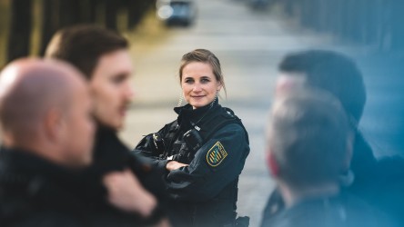 Polizeikommissarin Nadine in Uniform auf der Straße. Sie lächelt in die Kamera.