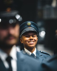 Ein junger Polizeimeisteranwärter in Uniform blickt mit einem Lächeln in die Kamera.