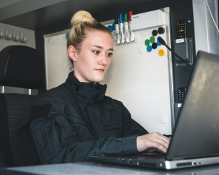 Eine Frau in Uniform sitzt an einem Laptop.